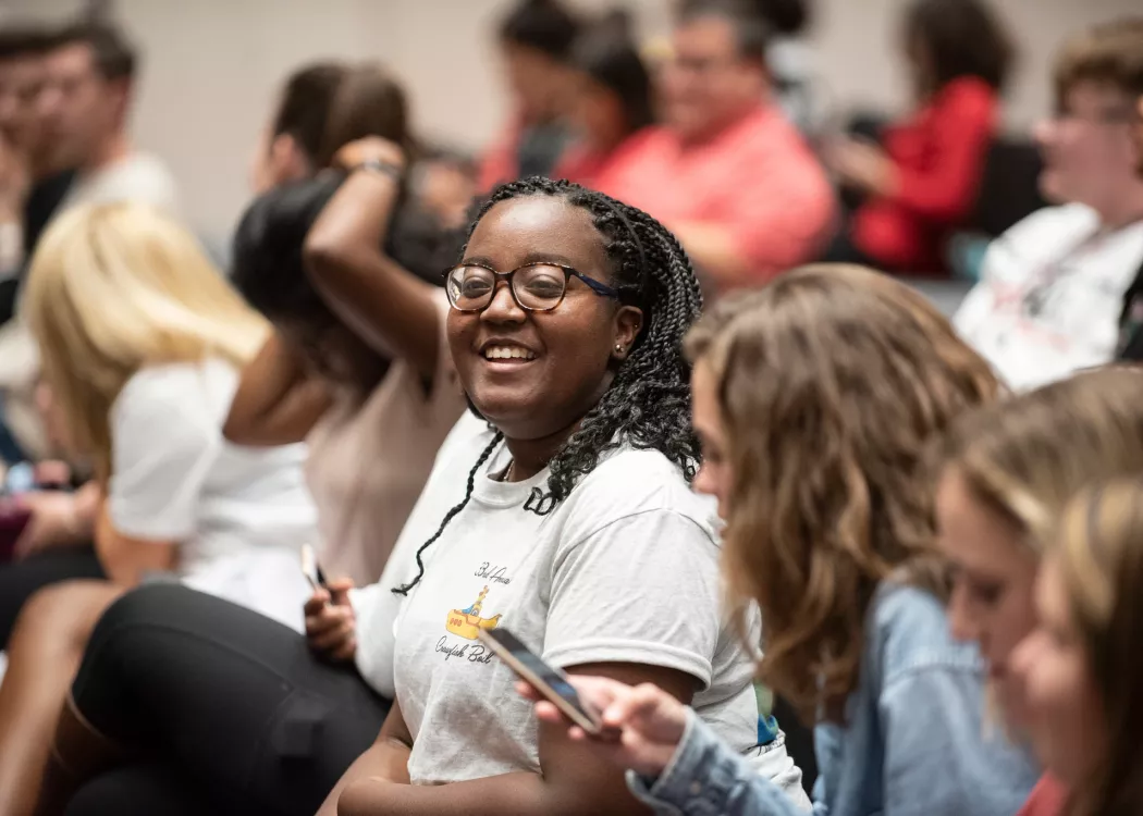 Smiling student in the audience at an Orientation event