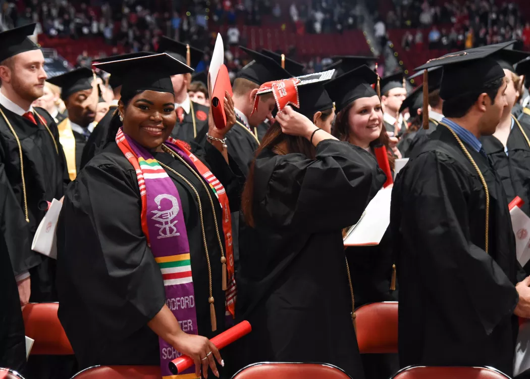 Student at commencement smiling and looking at the camera