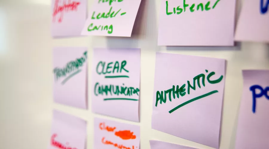 Close-up of sticky notes in an exercise. Notes in focus read "authentic, clear communication, great listener, transparent"