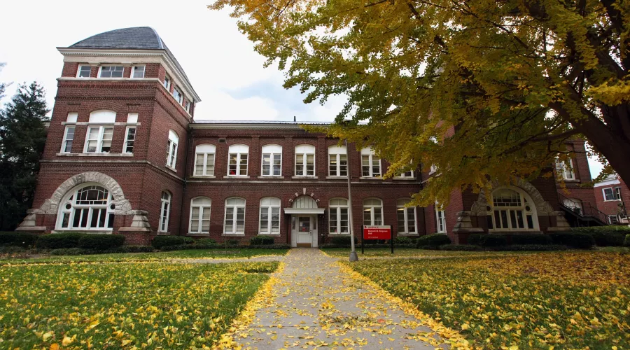 Front view of Brigman Hall at the University of Louisville with yellow leaves on the ground.