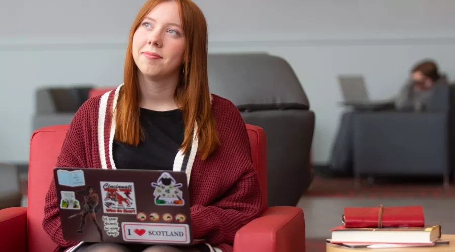 A student pauses in thought while working on a laptop in the Belknap Academic Building
