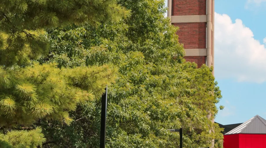Students walking across campus walkway into student union with the cloacktower in the background.
